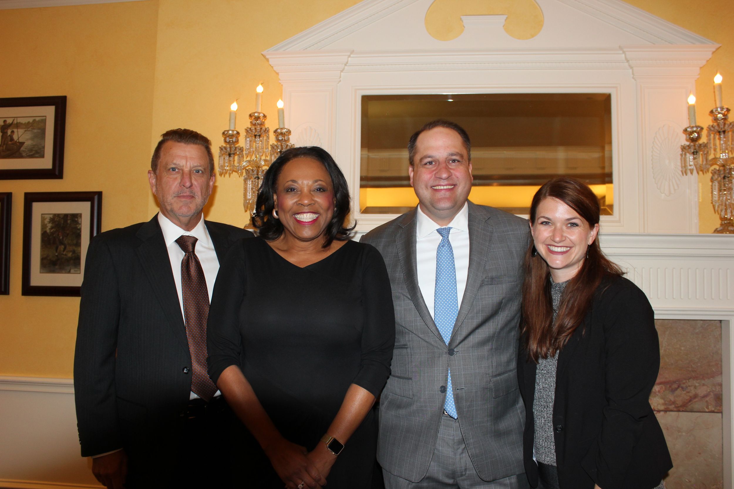 2017-18 Section Chair DJ Seidel, guest speaker Judge Vanessa Gilmore, 2018-19 Chair Andrew Pearce, and a section member pose in front of the Coronado Club's decorative wall.